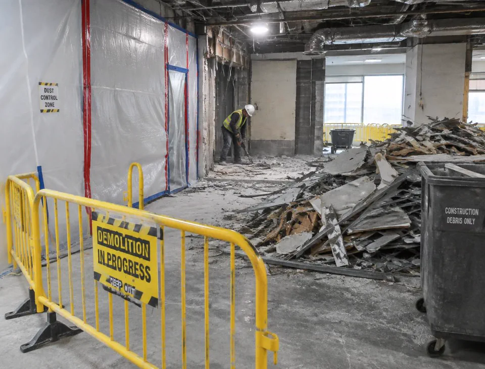 Interior demolition site with debris removal, dust barriers and safety barricades